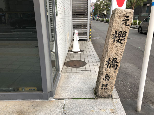 四つ橋筋東側の京富ビル南角。石碑が傾いている